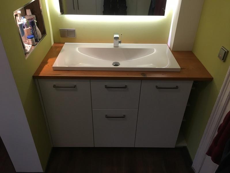 Weißes Waschbecken in Waschbeckenunterschrank mit Holzoberfläche und weißen Türen