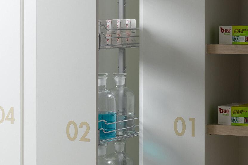 Detailaufnahme von Apothekerschränken Detailaufnahme von weißen Apothekerschränken mit dezenter Nummerierung und Ausziehschubladen.