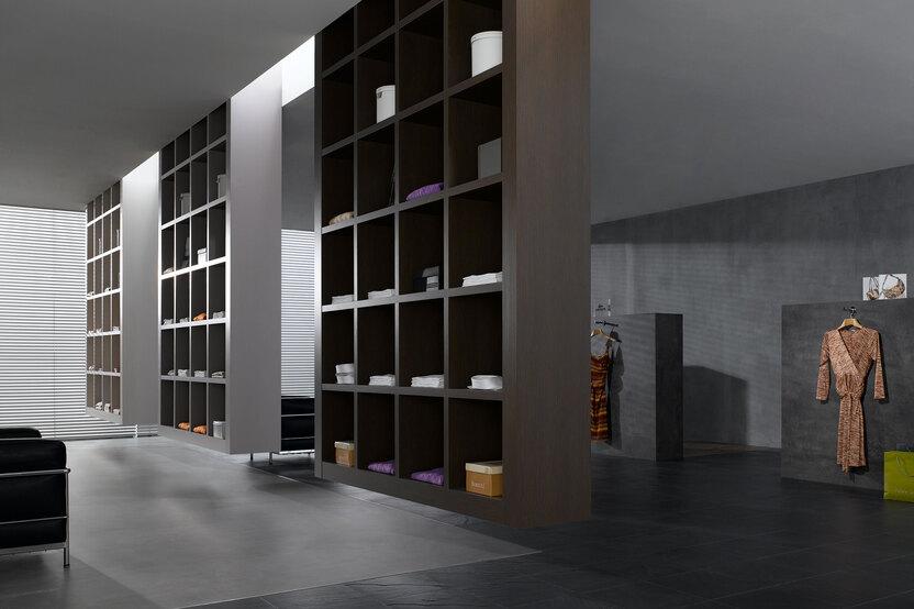 Impression eines geräumigen Regalsystems aus dunklem Holz in einem hochwertigen Bekleidungsladen